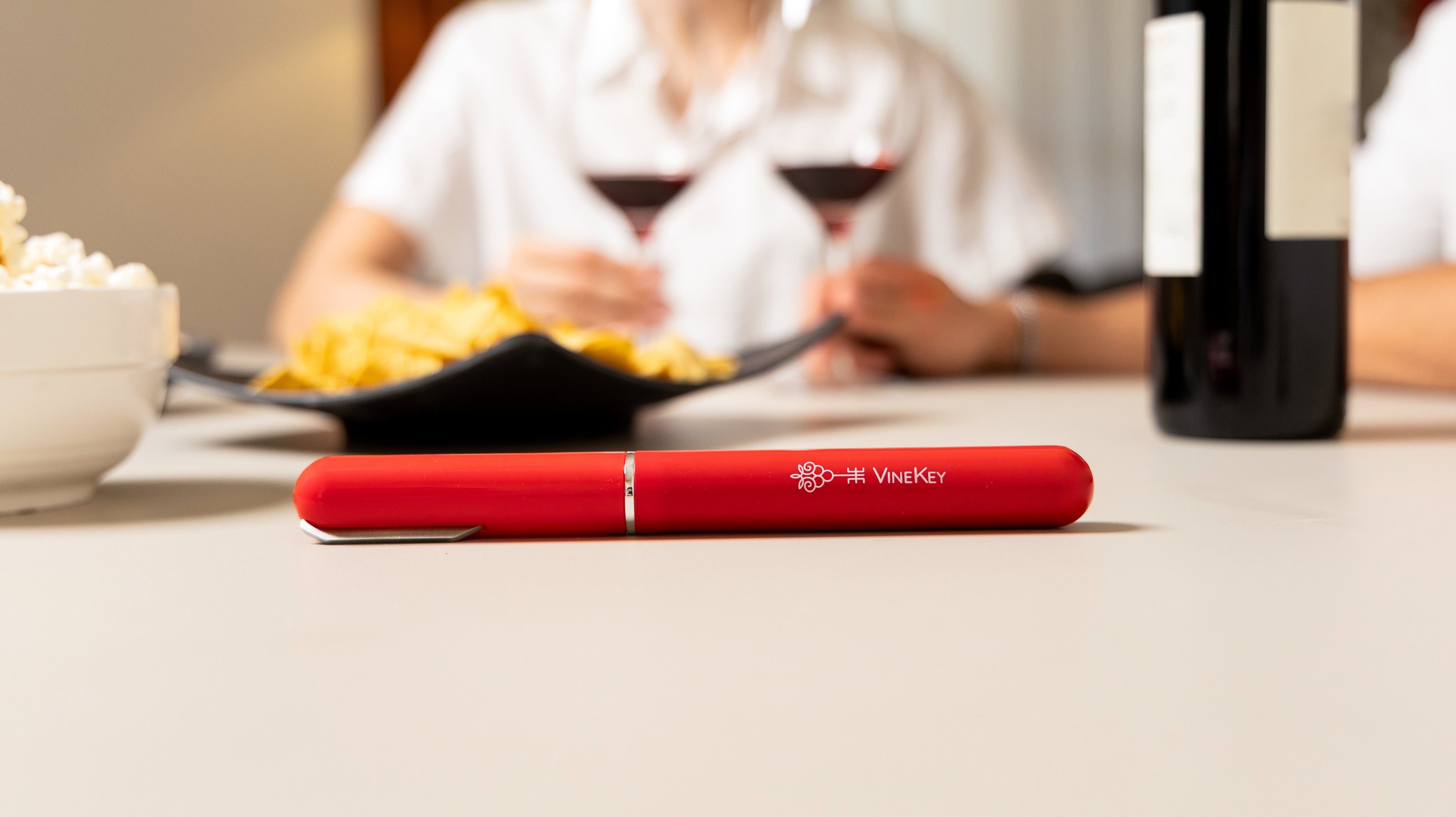 Desktop banner featuring the VineKey red air pump wine opener pen in a cozy lifestyle setting
