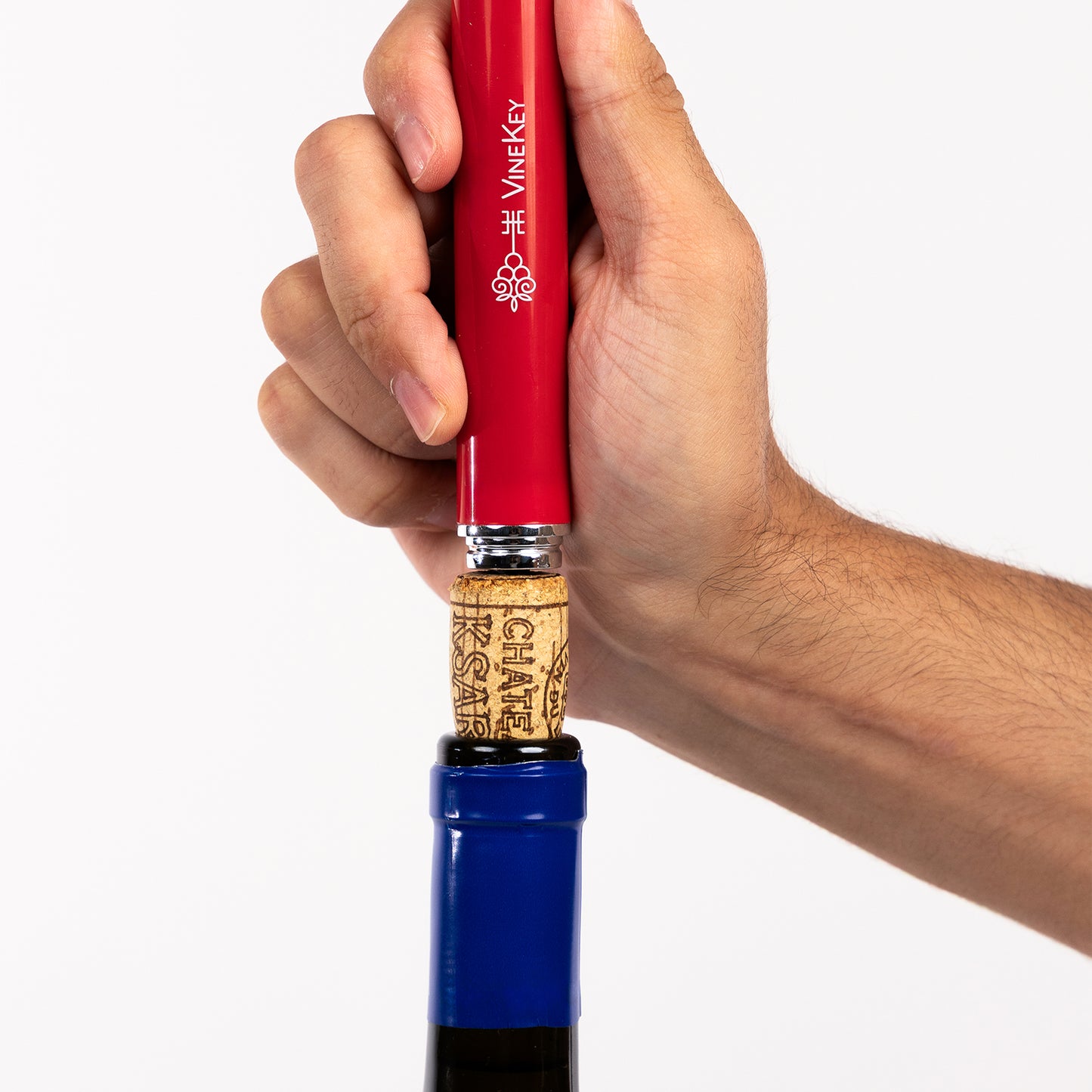Hand using the VineKey red air pump wine opener pen to remove a cork